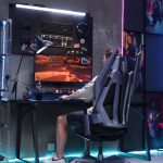 專業電競桌面配置圖，展示具備 RGB 燈效的顯示器、人因工程電競椅、專業級耳機及外接音訊 DAC 系統。